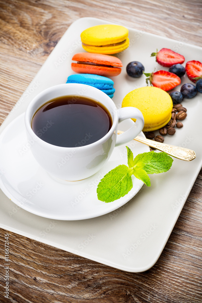 Cup of coffee with macaroons and berries on wooden background Cup of coffee with macaroons and berries on wooden background