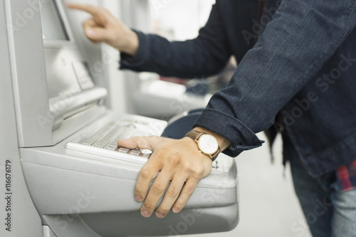 Midsection of man using ticket machine at railroad station photo