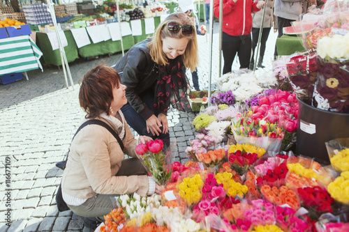 Happy mature women buying flowers at market stall