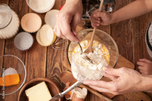 Woman hands, ingredients and devices for preparation muffin on a wooden background. House pastries. Food concept. Flour, eggs, butter, mix for pastries. 