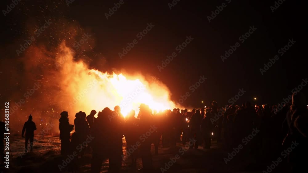 Many people meet at night near big fire