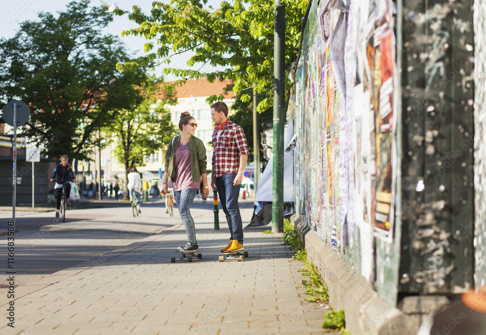 Full length of happy couple skateboarding on sidewalk