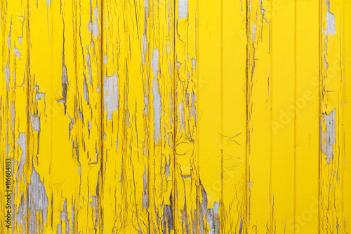 Vertical background of the old wooden planks with cracked yellow paint