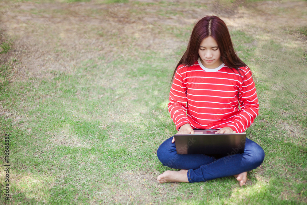 Portrait of happy young woman sitting on grass and using laptop Portrait of happy young woman sitting on grass and using laptop