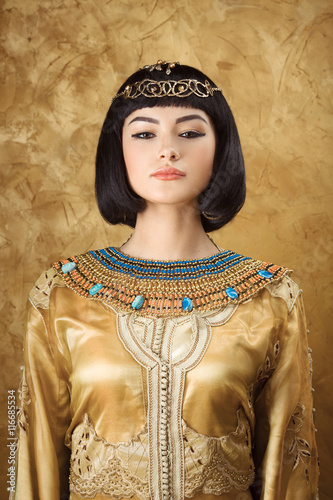 Foto Beautiful Egyptian woman like Cleopatra on golden background