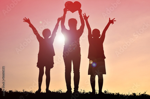 Silhouette mother and children holding heart shape at sunset. Concept mother day