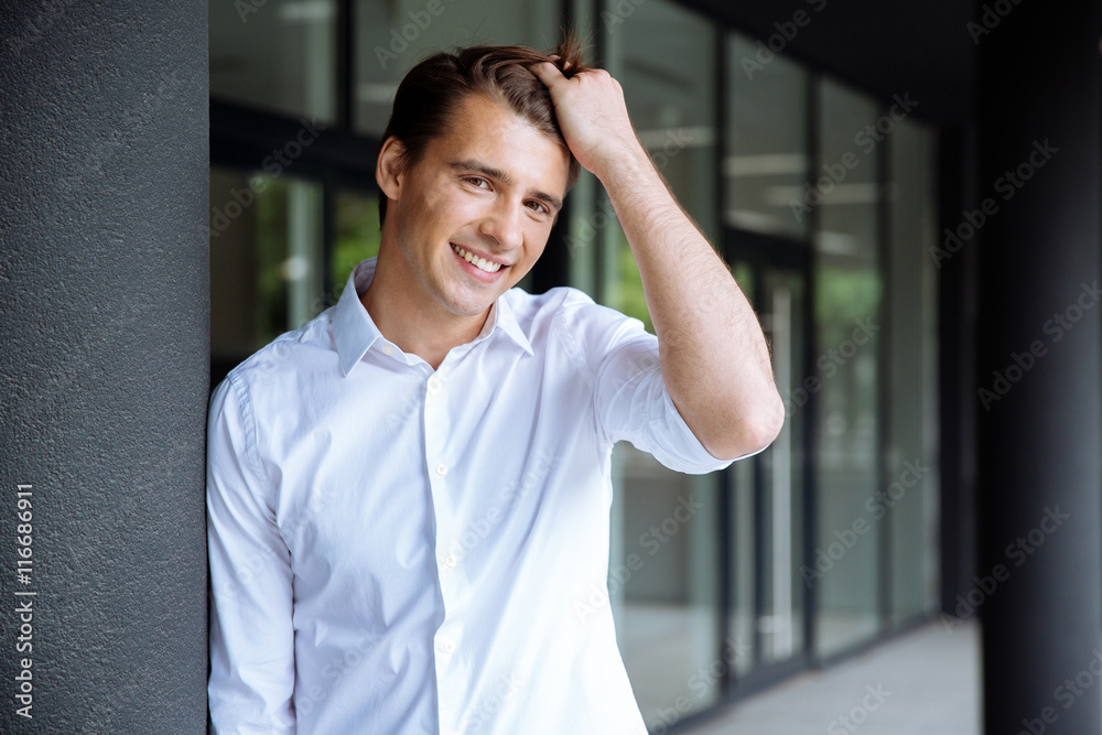 Cheerful confident young businessman standing and smiling Cheerful confident young businessman standing and smiling