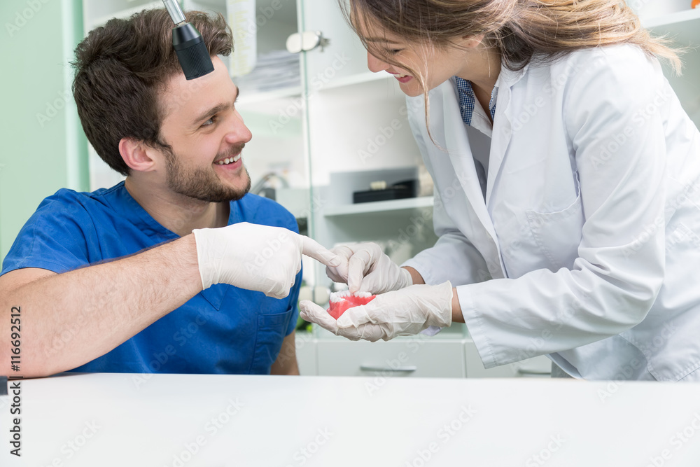 Dental prosthesis, dentures, prosthetics work. Prosthetics hands while working on the denture, false teeth, a study and a table with dental tools. Dental prosthesis, dentures, prosthetics work. Prosthetics hands while working on the denture, false teeth, a study and a table with dental tools.