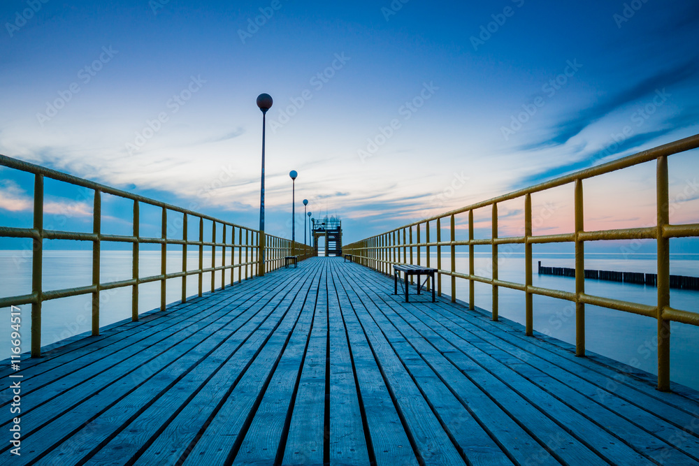 Pier on the sea at sunset. Lanterns and benches. Lonely landscape and dramatic sky. Pier on the sea at sunset. Lanterns and benches. Lonely landscape and dramatic sky.