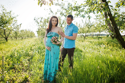 Happy pregnant couple at turquoise dress on the garden © AS Photo Family