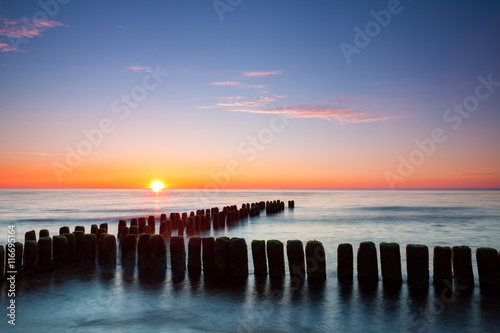 Sunset at Baltic sea  view on old breakwater piles.