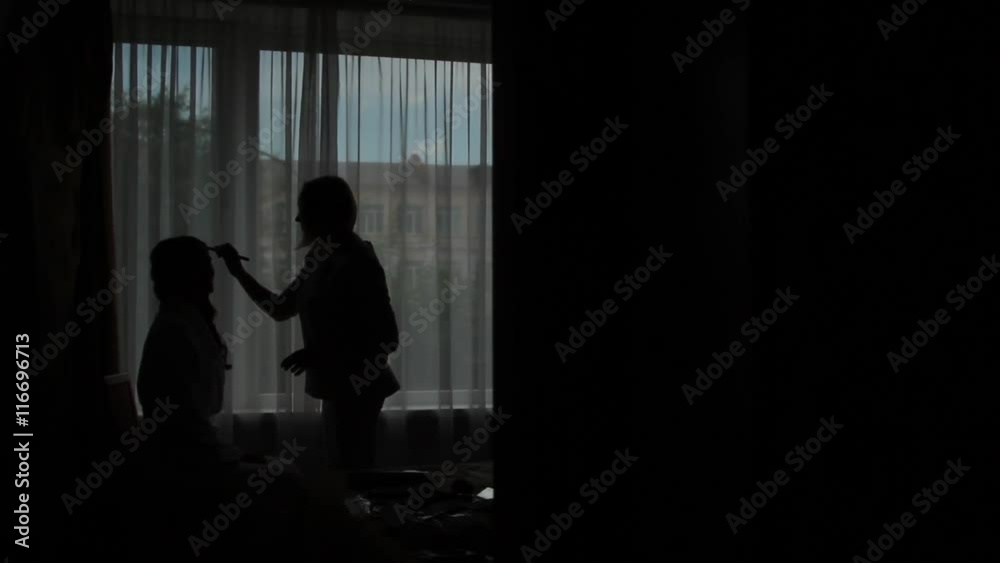 Stylist makes makeup against the window. Silhouettes of people. Stylist makes makeup against the window. Silhouettes of people.