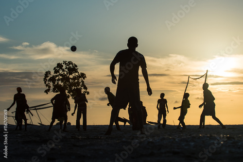 African men playing football on the beach at sunset