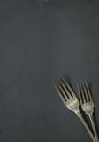 Antique style forks on a rustic slate background forming a page border