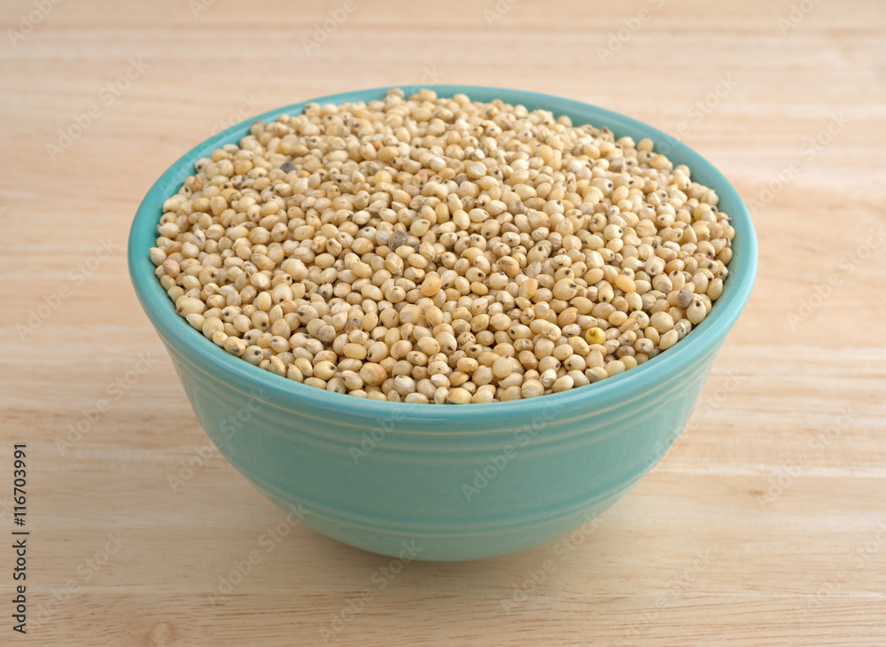 Whole grain sorghum seeds in a bowl on a table. Whole grain sorghum seeds in a bowl on a table.