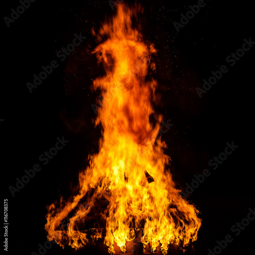 Wooden house roof in fire on black background