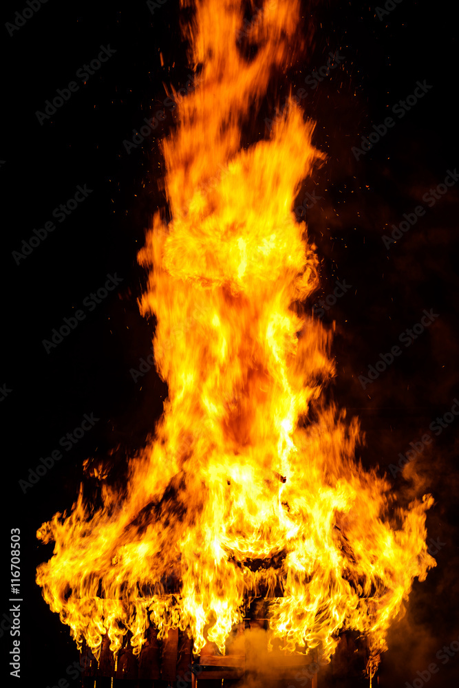 Wooden house roof in fire  on black background