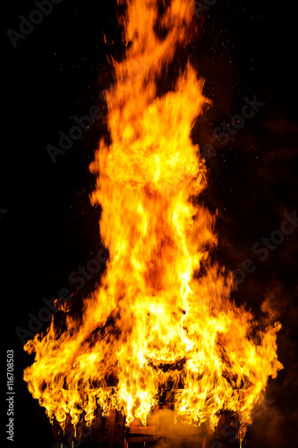Wooden house roof in fire on black background