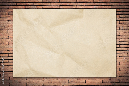 Recycled crumpled brown paper on old brick wall dark edged with copy space for text or image.