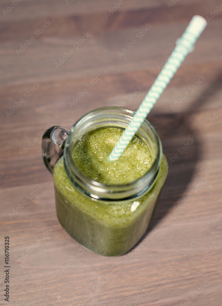 A green smoothie in a mason jar on wooden background A green smoothie in a mason jar on wooden background