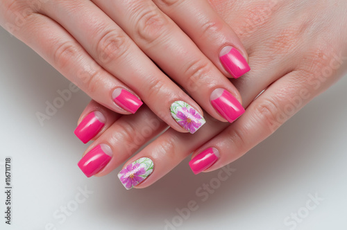 pink long square manicure with flowers on the ring finger on a white background