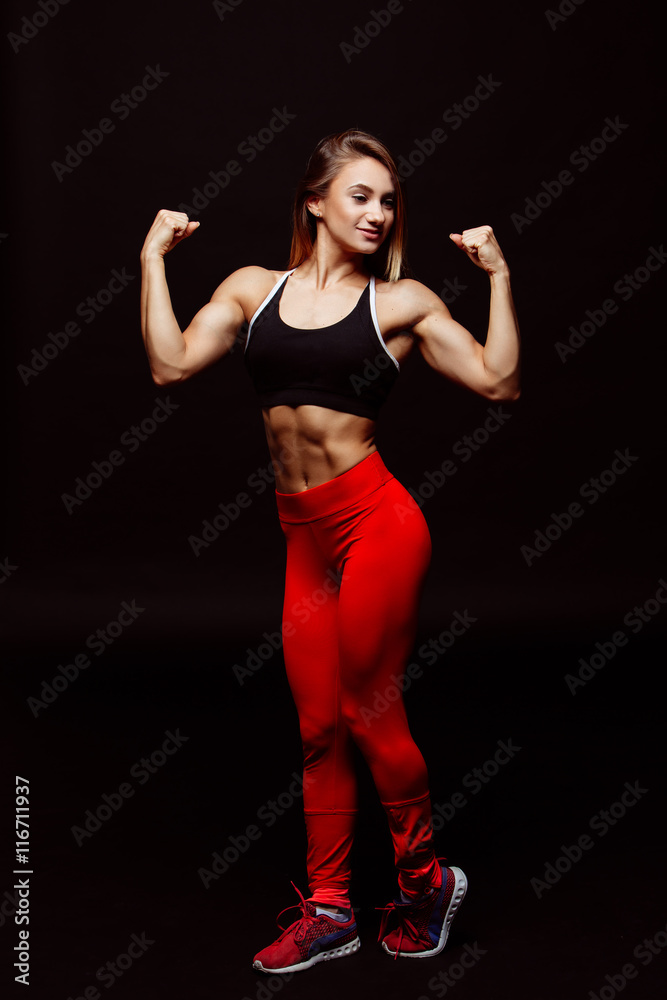 Image of muscular young woman posing in sportswear against black Image of muscular young woman posing in sportswear against black