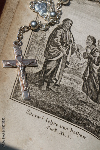 Eine Seite in einem Gebetsbuch von 1824 darauf ein silberner Rosenkranz photo