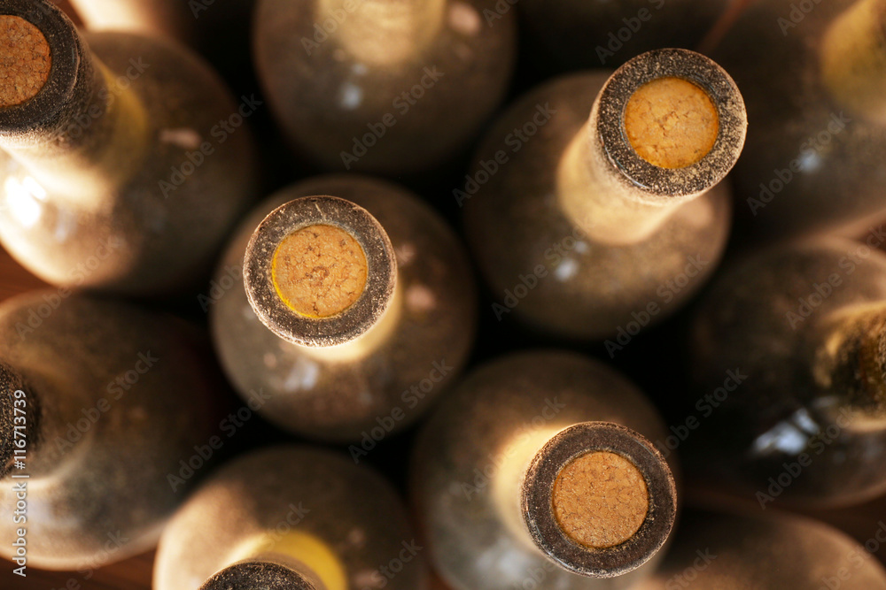 Stacks of dusty wine bottles on wooden background, upside view. Close up Stacks of dusty wine bottles on wooden background, upside view. Close up
