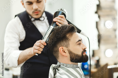 Dark haired barber doing a haircut