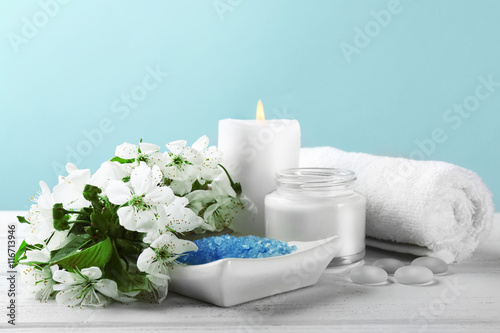 Spa treatment with blooming branch on white wooden table