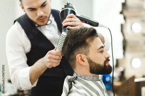Dark haired barber doing a haircut