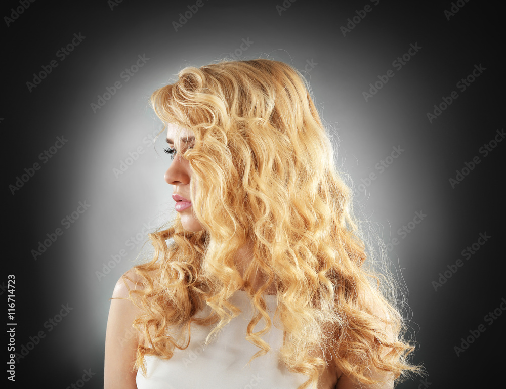 Portrait of young woman with blonde hair on dark background Portrait of young woman with blonde hair on dark background