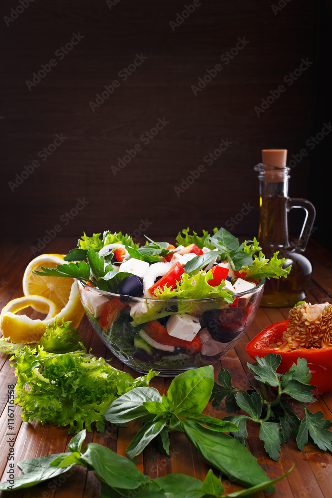 Greek salad with olive oil in a glass bowl. Fresh vegetables and herbs. A place for inscriptions.