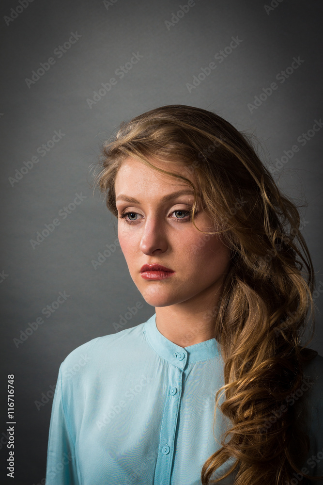 Beautiful blonde in a blue blouse on a dark gray background. Beautiful blonde in a blue blouse on a dark gray background.
