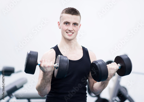 Athletic man with a dumbells in gym