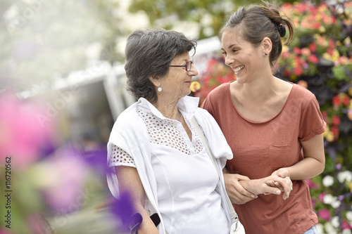Home carer helping disabled woman walking with crutch