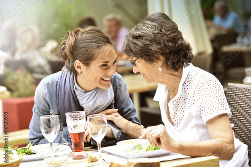 Senior woman with home carer having lunch at restaurant