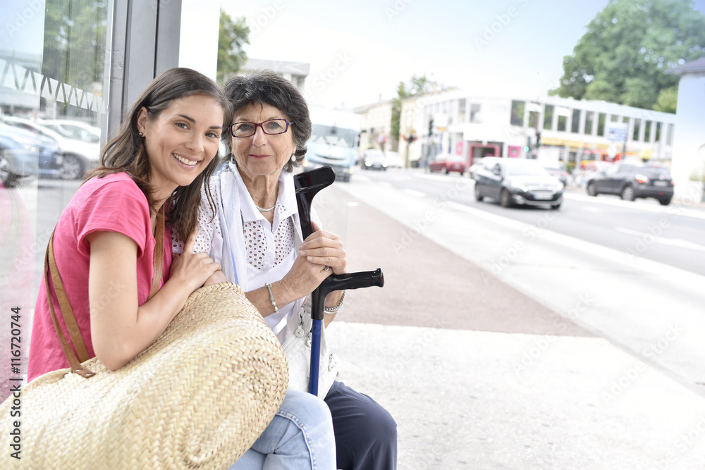 Senior woman with home carer waiting for the bus