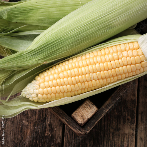 Fresh corn on cobs on rustic wooden table, closeup