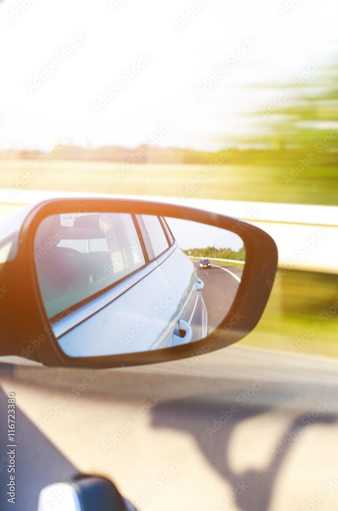 Concept of speed. Car driving on the road. Reflection in a car mirror.Rear view mirror reflection. Blurry background.