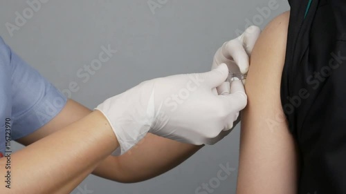 Doctor injecting flu vaccine to patient's arm in local hospital