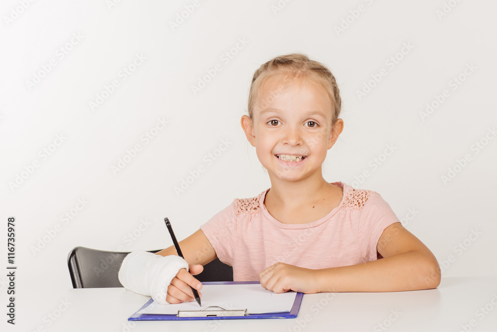 smiling little girl with broken arm is sitting at the table smiling little girl with broken arm is sitting at the table