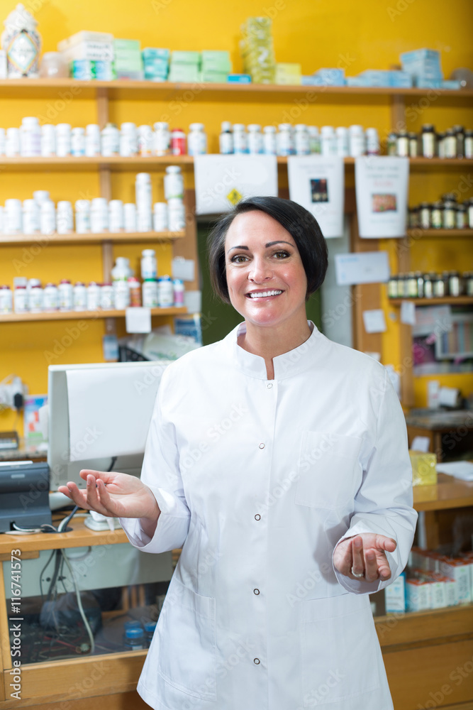 Glad woman in uniform standing in pharmacy