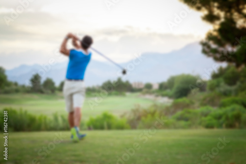 Man playing golf on a golf course in the evening with image blur applied. Background. Copy space.