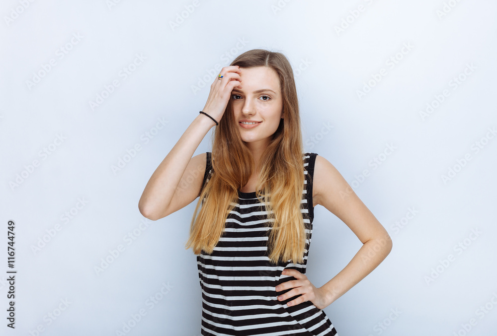 Portrait of happy young beautiful woman in striped shirt touching her hair posing for model tests against white studio background Portrait of happy young beautiful woman in striped shirt touching her hair posing for model tests against white studio background