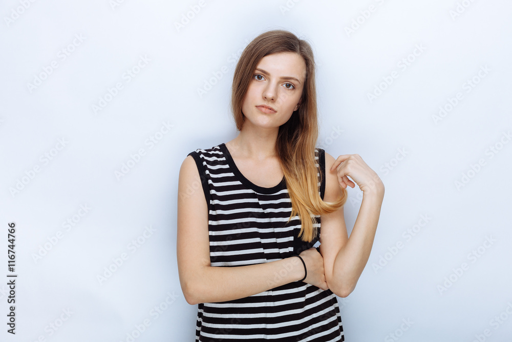 Portrait of happy young beautiful woman in striped shirt touching her hair posing for model tests against white studio background Portrait of happy young beautiful woman in striped shirt touching her hair posing for model tests against white studio background