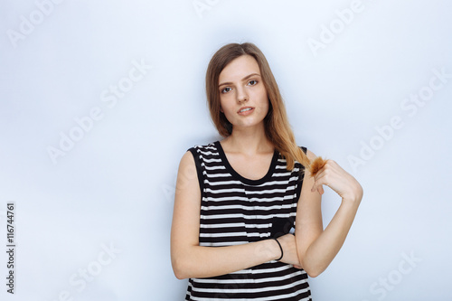 Portrait of happy young beautiful woman in striped shirt touching her hair posing for model tests against white studio background