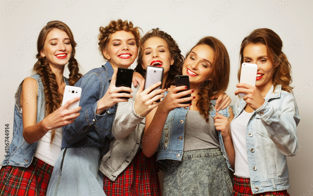 group of young women looking at their smartphones group of young women looking at their smartphones