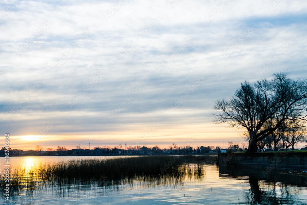 Sun at sunset with reflections on a lake with reeds Sun at sunset with reflections on a lake with reeds