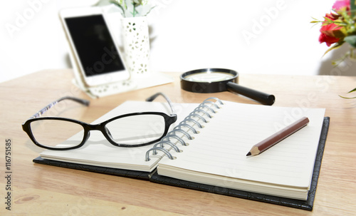 Open Blank notebook and pencil with magnifying glasses and